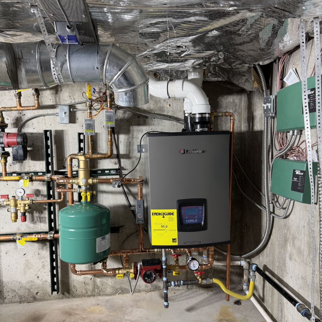 Lochinvar Noble 150 Boiler Installed A high efficiency boiler system with an ENERGYGUIDE label is installed on a basement wall, surrounded by pipes, valves, gauges, and control panels.